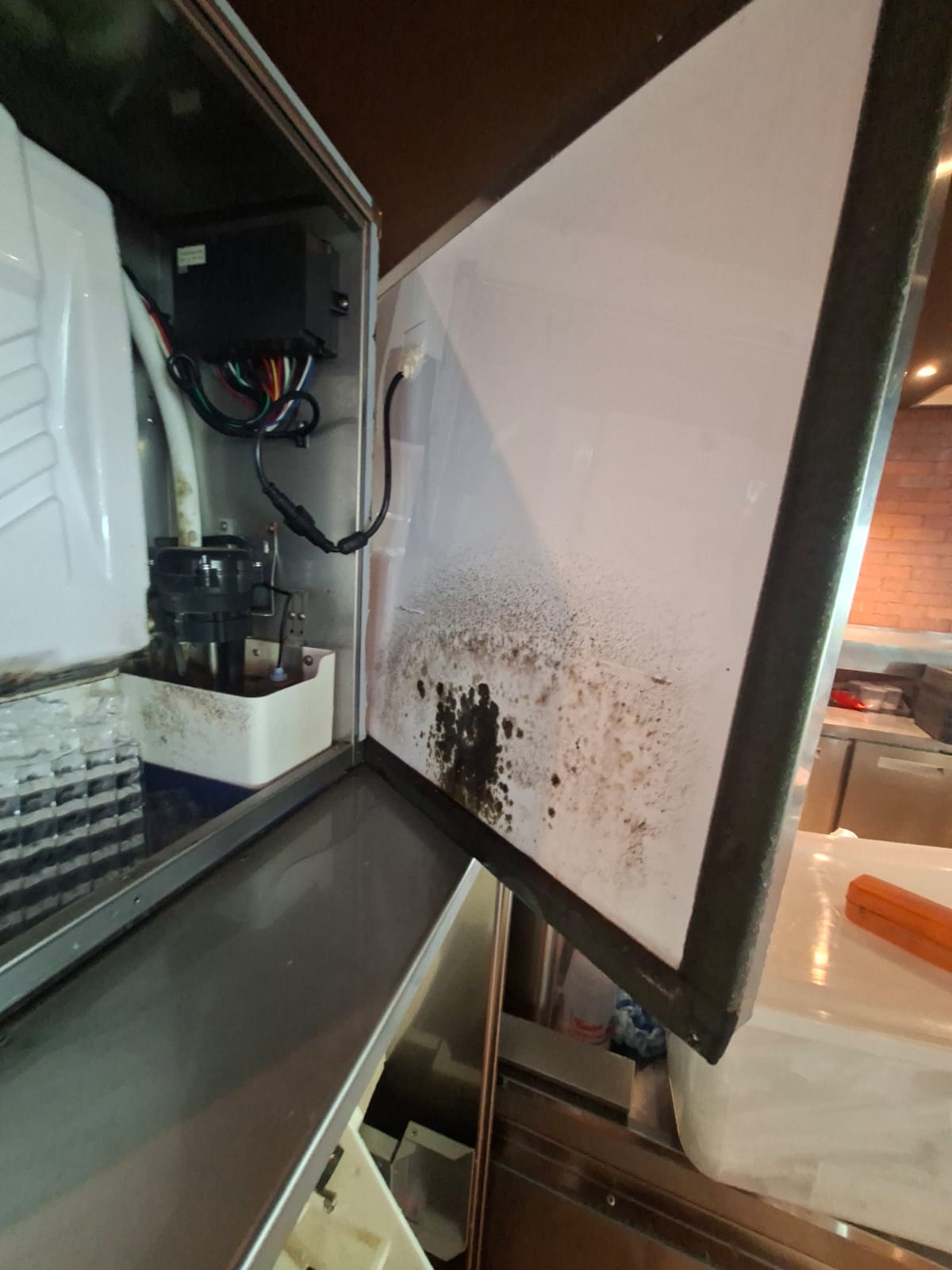 Acúmulo visível de sujeira no interior de uma máquina de gelo antes da limpeza
